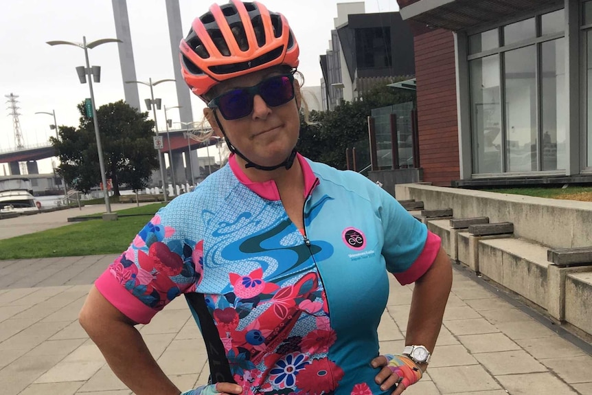 A woman in Lycra stands over her bike with her hands on her hips