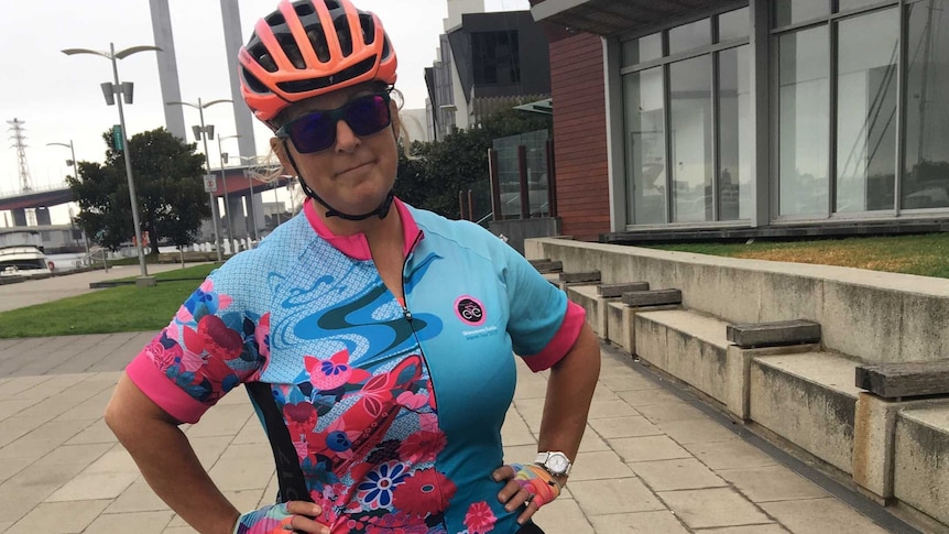 A woman in Lycra stands over her bike with her hands on her hips
