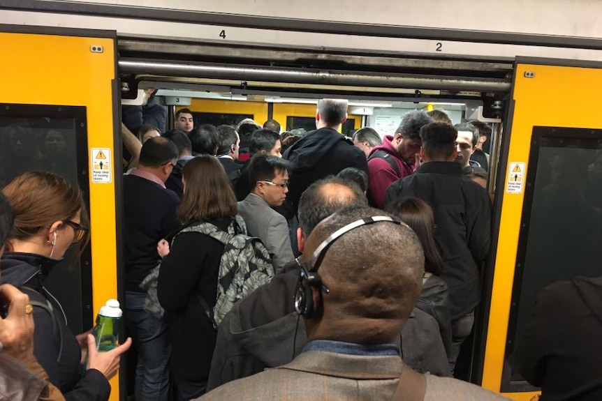 People crowd into a train carriage.