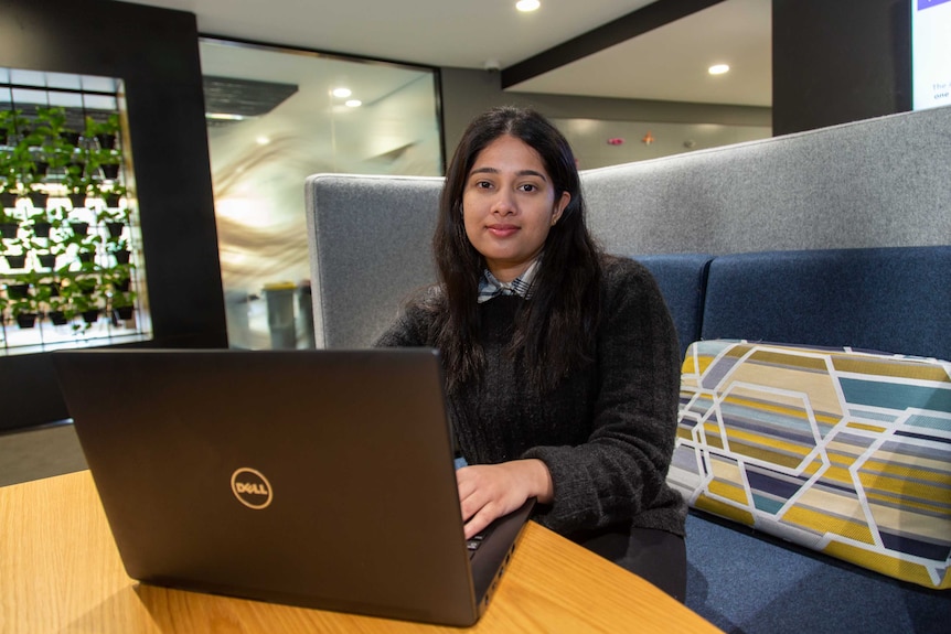 Derani Dissanayake (researcher) sits in front of laptop computer.