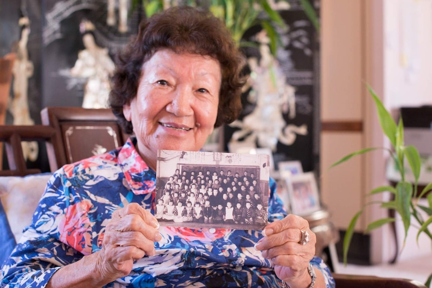 Kay Fisher holds up a black and white photograph of the class she taught during the final years of World War II.
