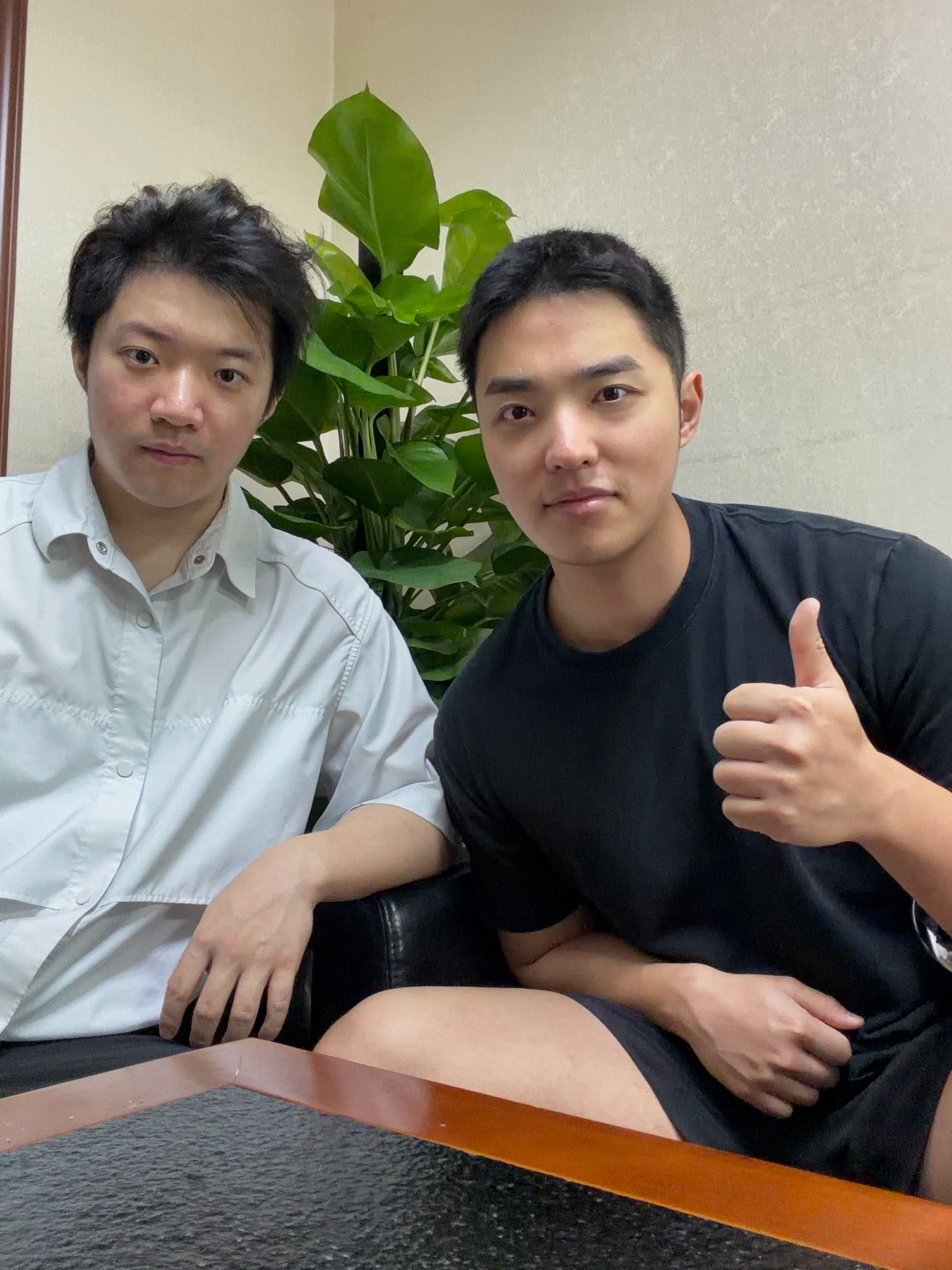 Two men are sitting next to each other and looking at the camera.
