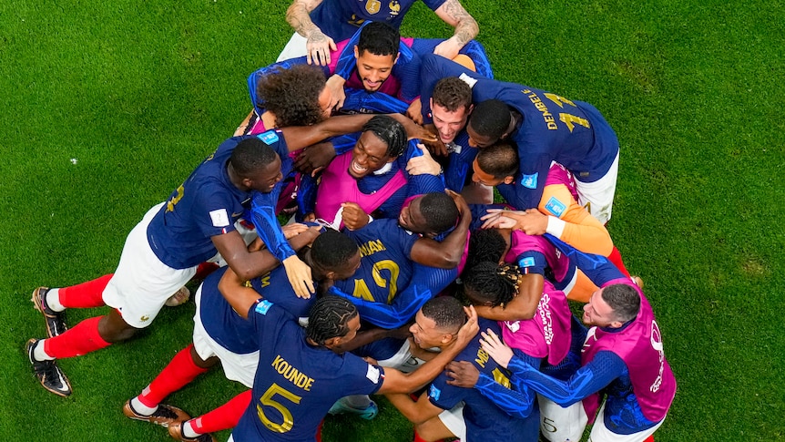 An overhead view of a scrum of French football players hugging and celebrating a goal
