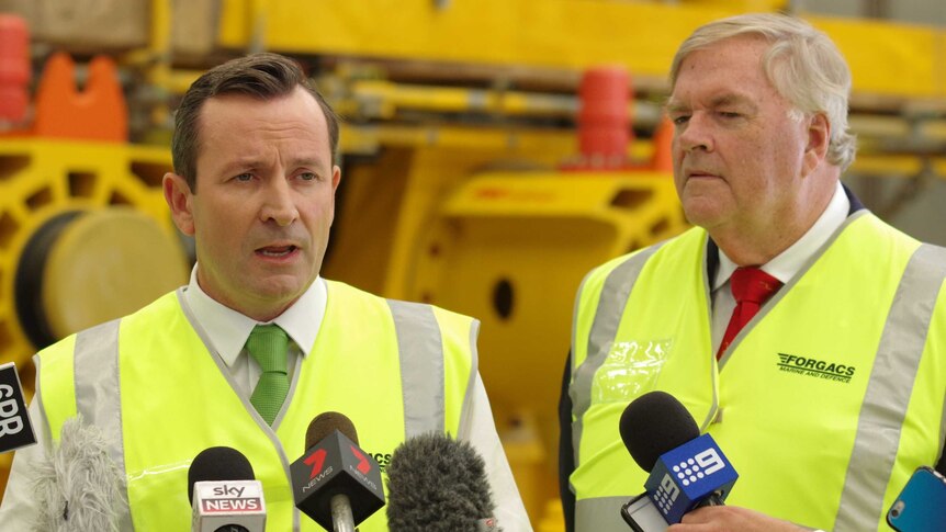Mark McGowan and Kim Beazley wearing high-vis vests in front of microphones.