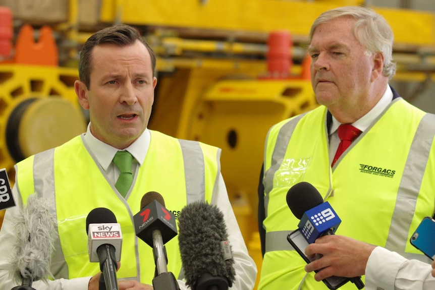 Mark McGowan and Kim Beazley wearing high-vis vests in front of microphones.