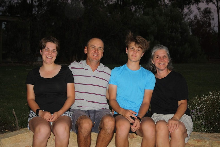 Two teenagers with their mum and dad, smiling to camera.