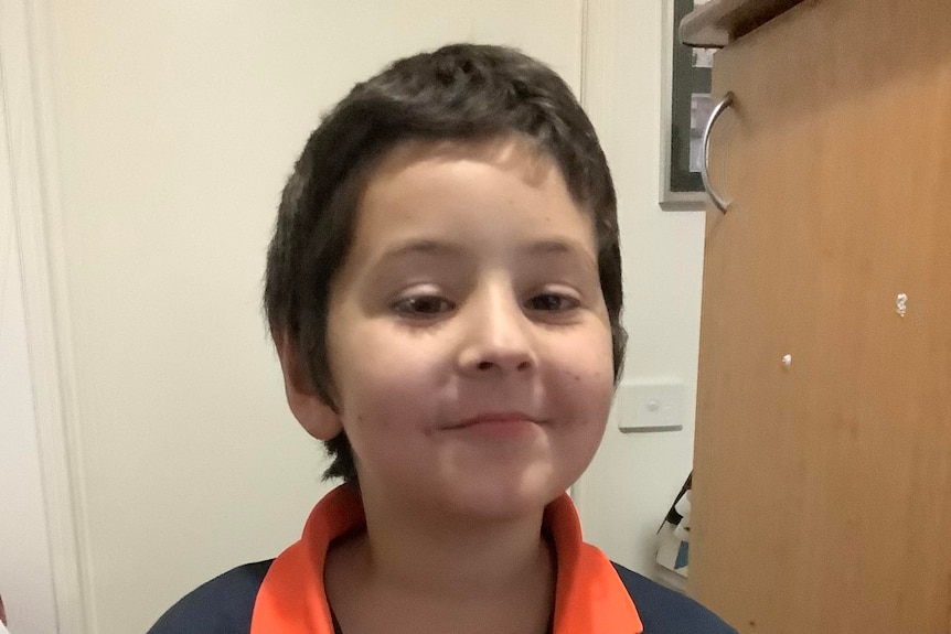A boy looking at the camera smiling slightly. 