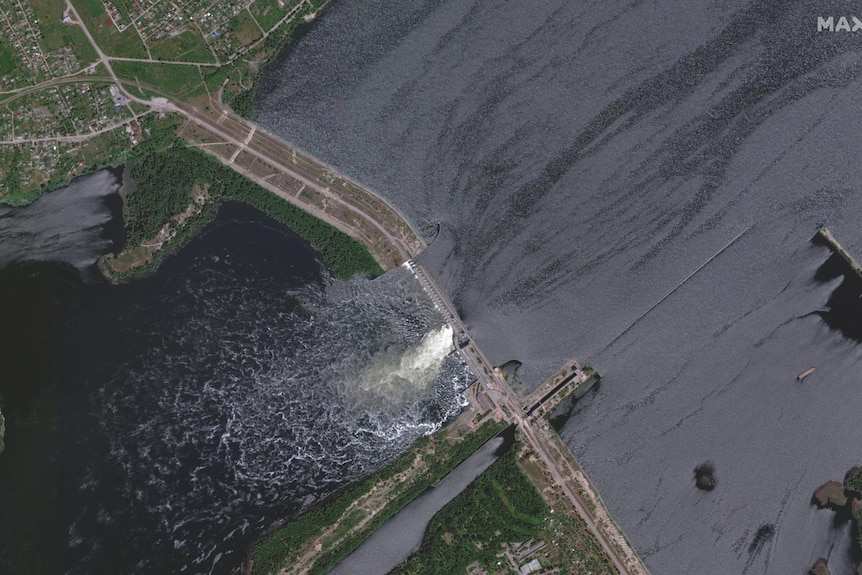 A bird's eye view of a dam split down the middle, hit by russian forces.
