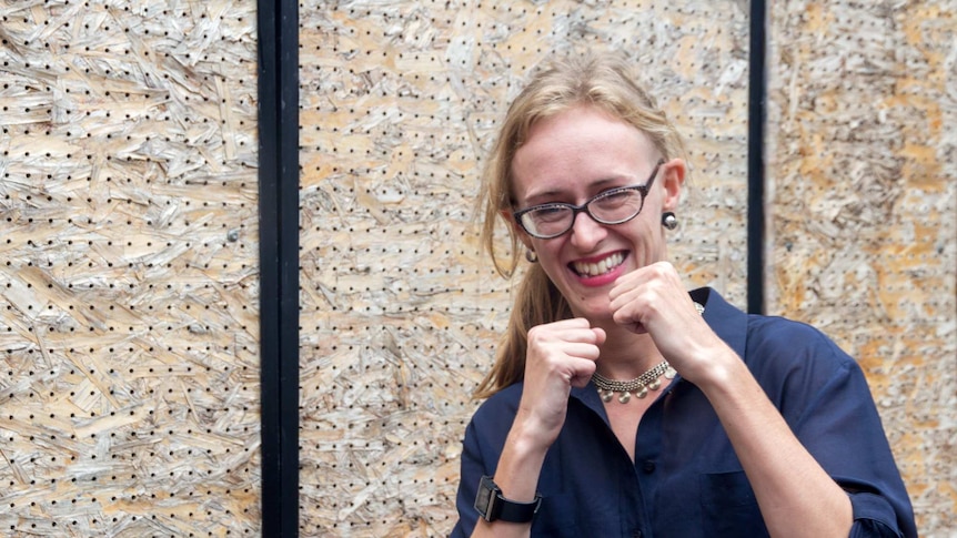 A woman smiles while holding up her fists in a fighting position