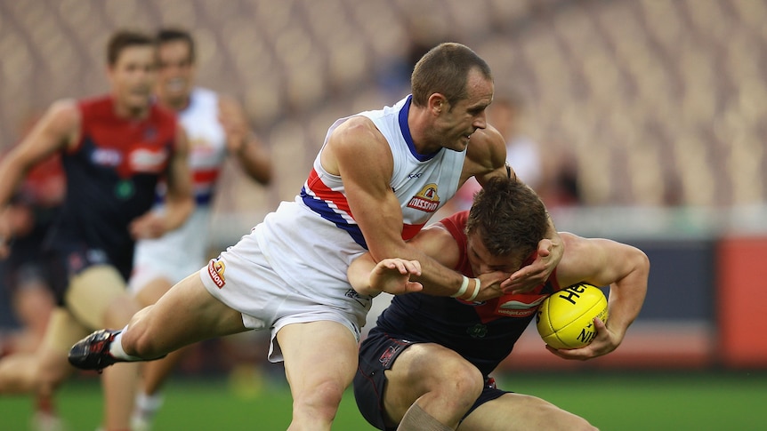 Collared ... Daniel Cross lays a tackle on Demons midfielder Jack Trengove.