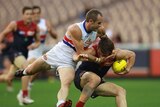 Collared ... Daniel Cross lays a tackle on Demons midfielder Jack Trengove.