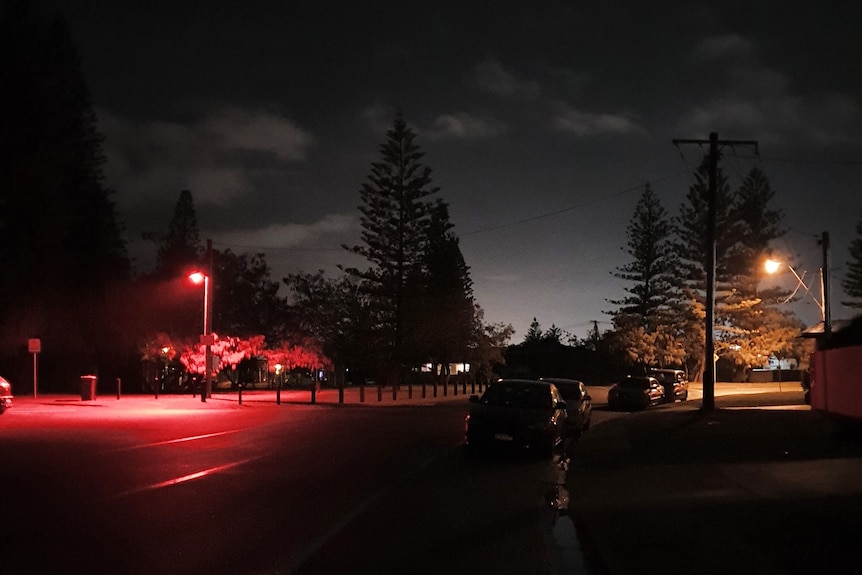 Picture shows two street lights, one glowing red, the other orange.