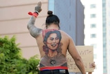 A man with a tattoo of Aung San Suu Kyi holds up a three-finger salute.