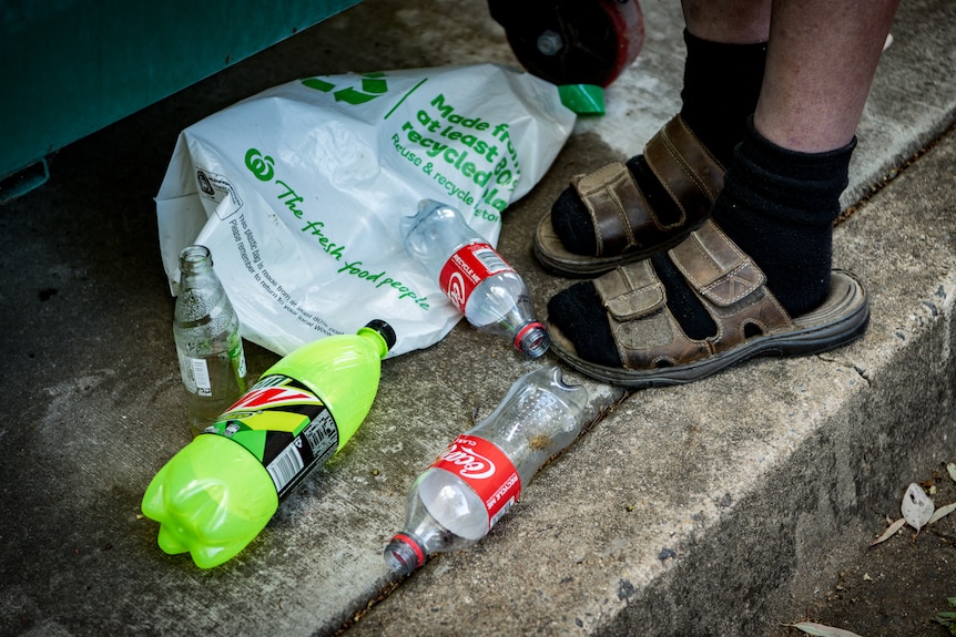 Peter Ristic wearing socks and sandals with cans near his feet. 