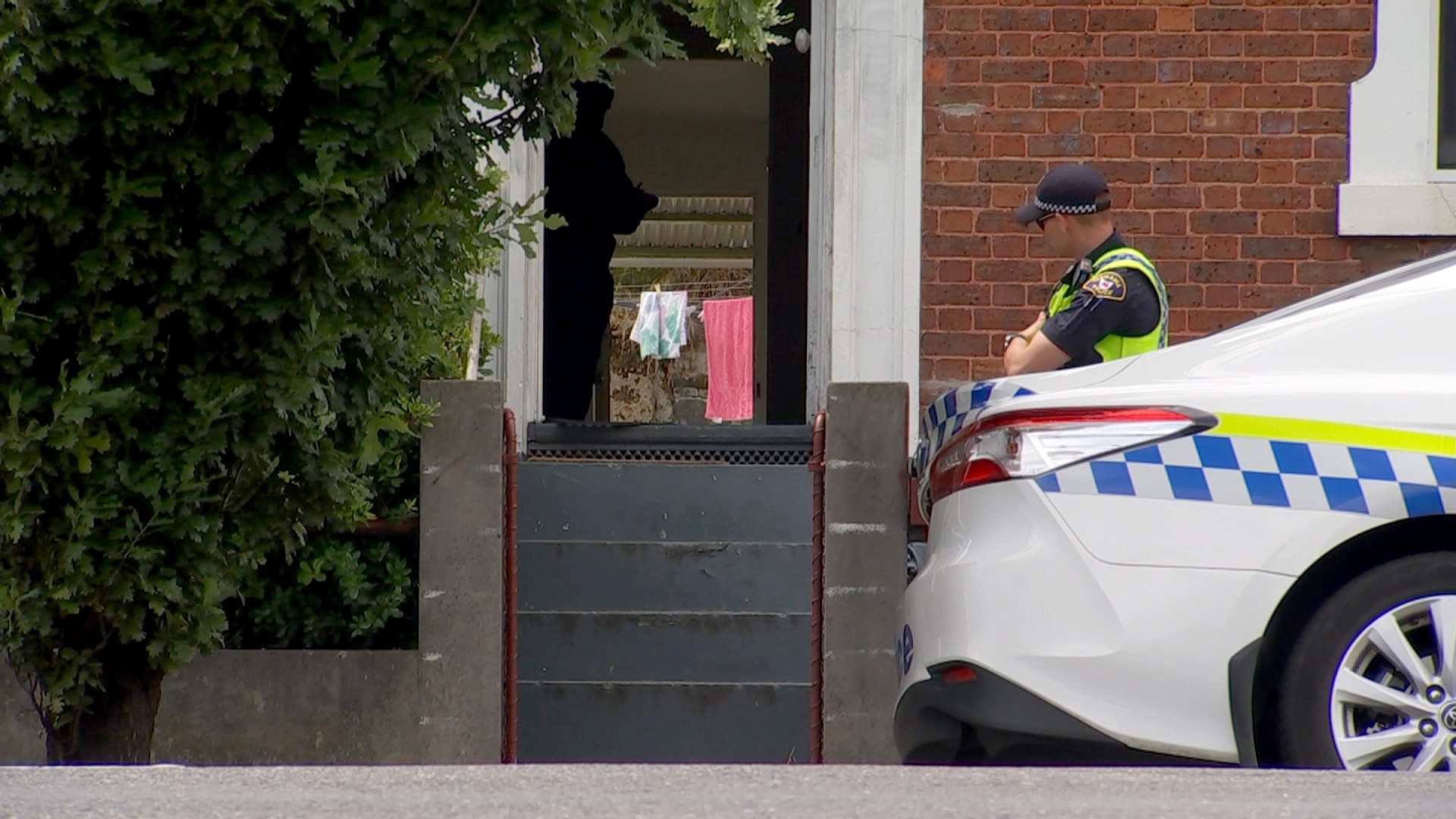 警车和警员停在一栋砖房外。