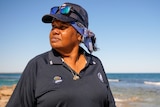 A woman at a beach wearing a cap, gazing sideways