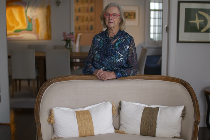 Woman stands behind a white and beige couch