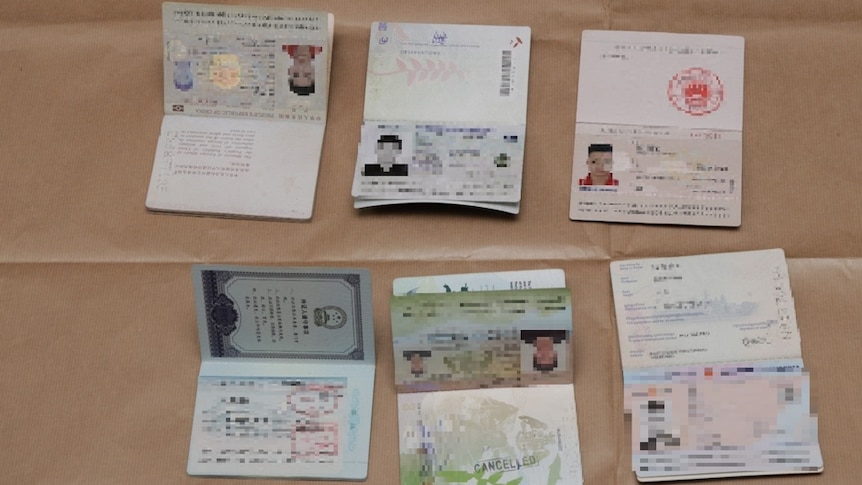 Six passports with details blurred out sitting open on a table. 