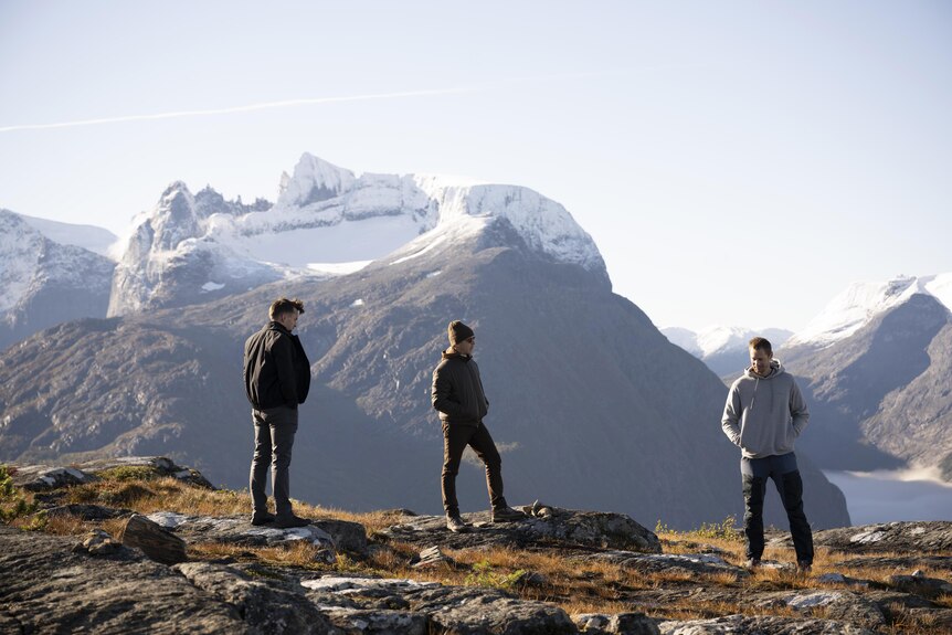 The three men stand on a mountain in Norway. 