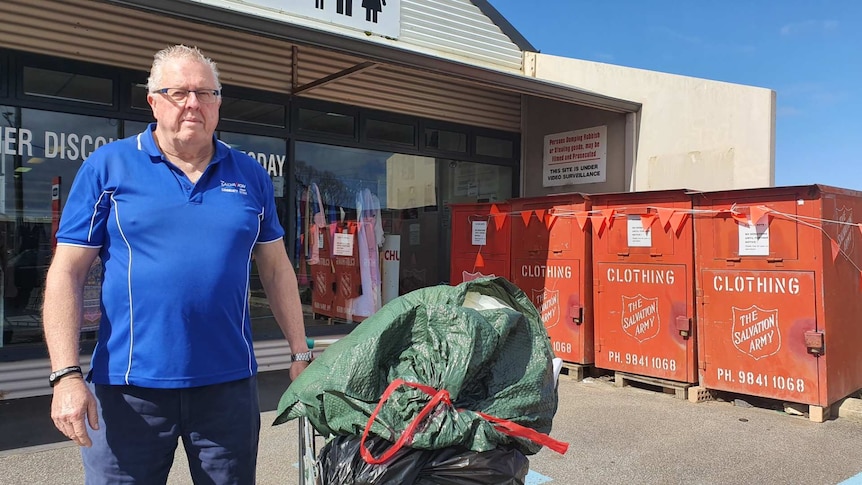 An older man stands with a trolley full of donations outside the Albany Salvation Army Op Shop.