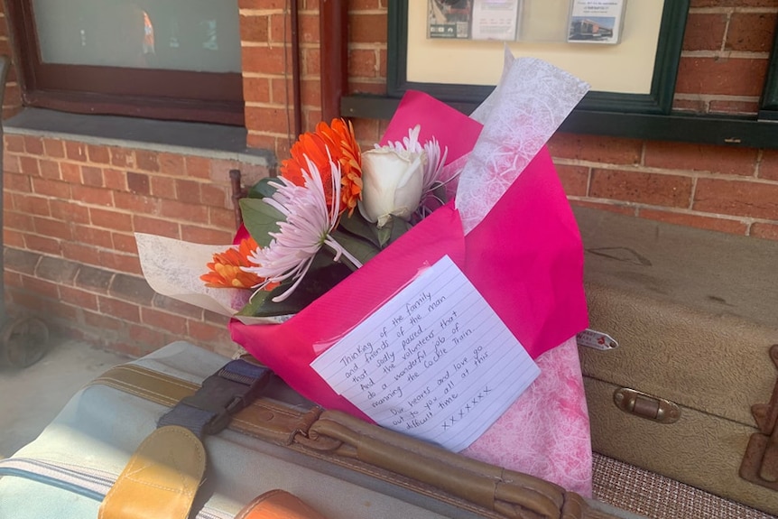 A bright bunch of flowers wrapped in pink paper, with a note attached.