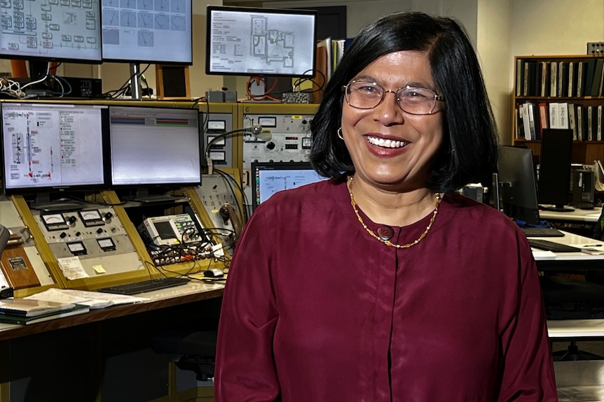 A woman in a burgundy shirt and glasses smiles.