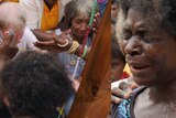 A composite image of Sean Dorney in PNG and a woman praying.