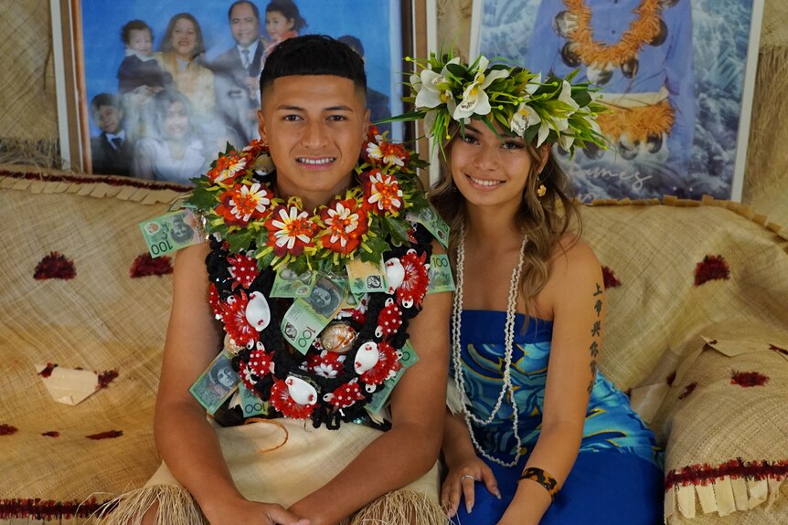 Tevita and Sharon Ta'ai's son ub traditional Tongan dress posing with a demale friend who has flowers in her hair.
