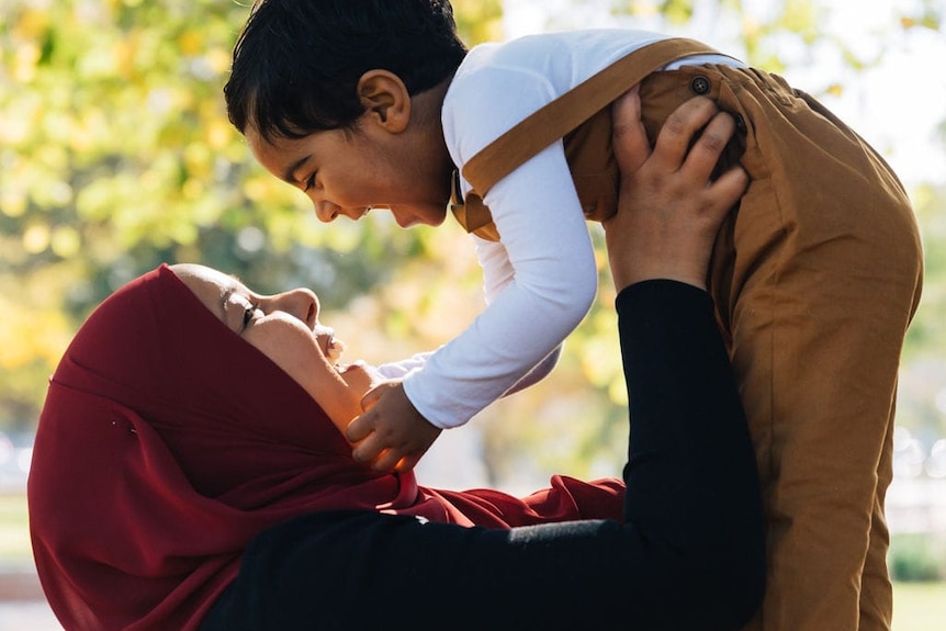 Inaz holding her son up above her head.