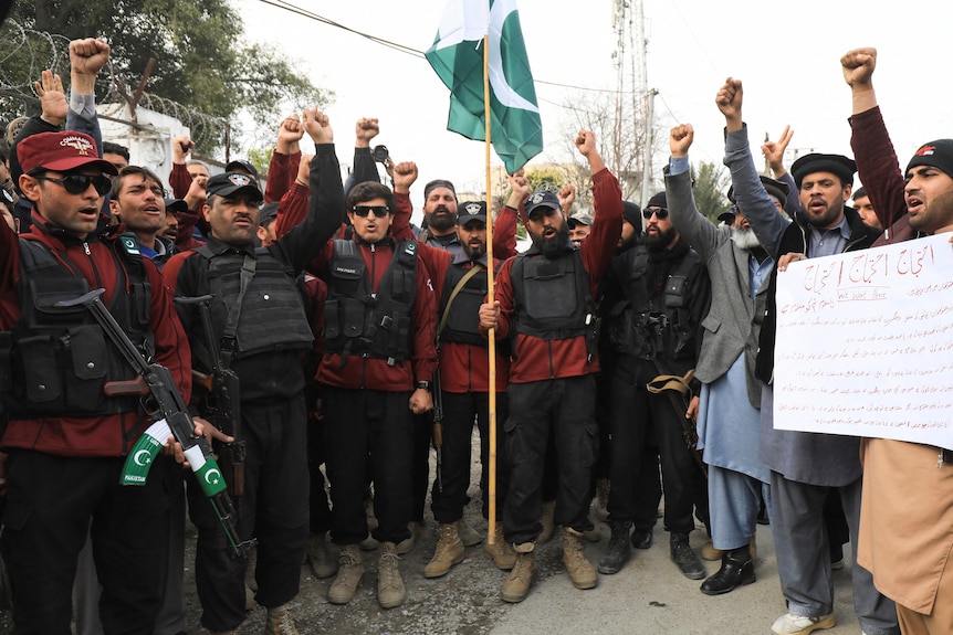 Peshawar police officers gather with fists raised to condemn a deadly suicide blast.