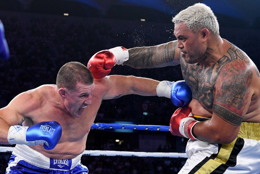 Paul Gallen bends down and punches Mark Hunt in the chest as Hunt aims a punch towards Gallen's head