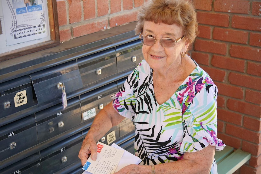 Jill Stretton opens her mailbox which is inside a small mail centre amongst other mailboxes