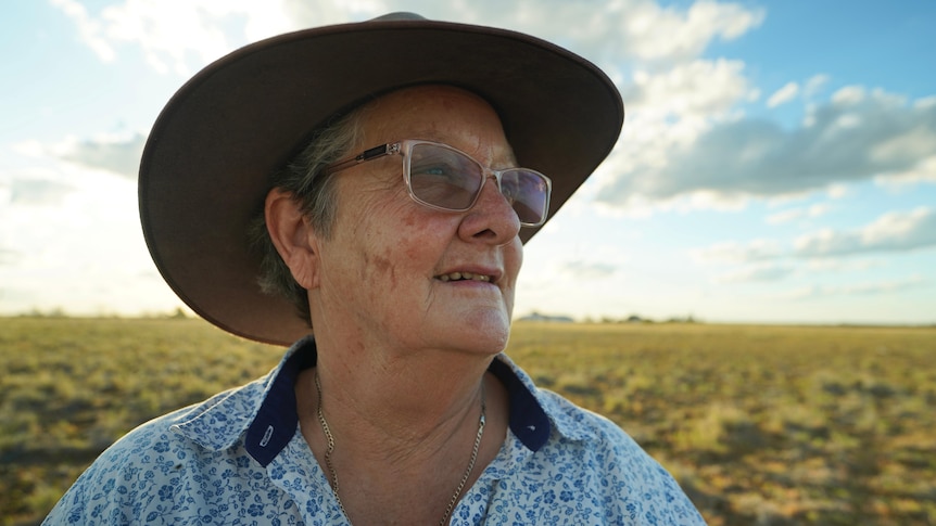 Woman in hat staring out at paddock