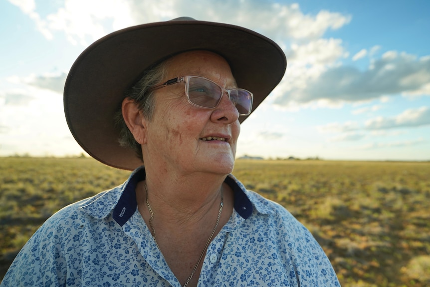 Woman in hat staring out at paddock