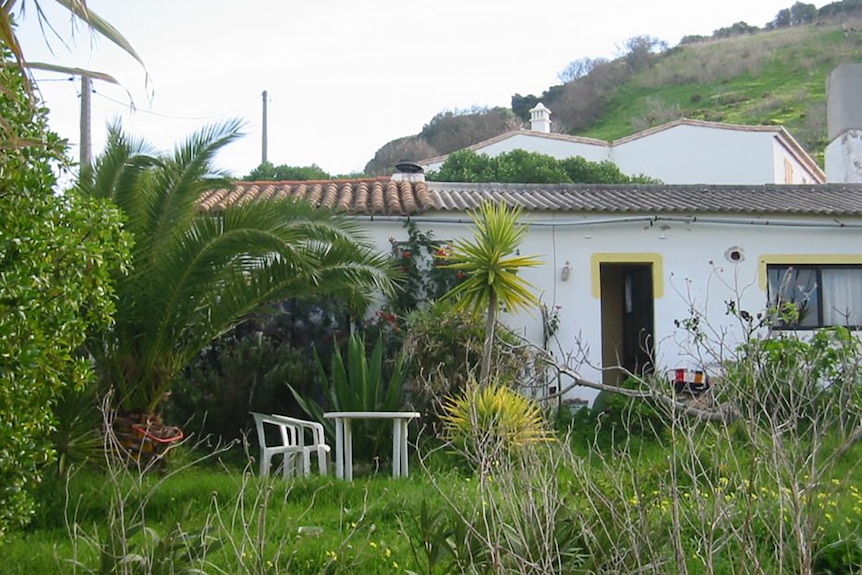 A white house with an overgrown garden