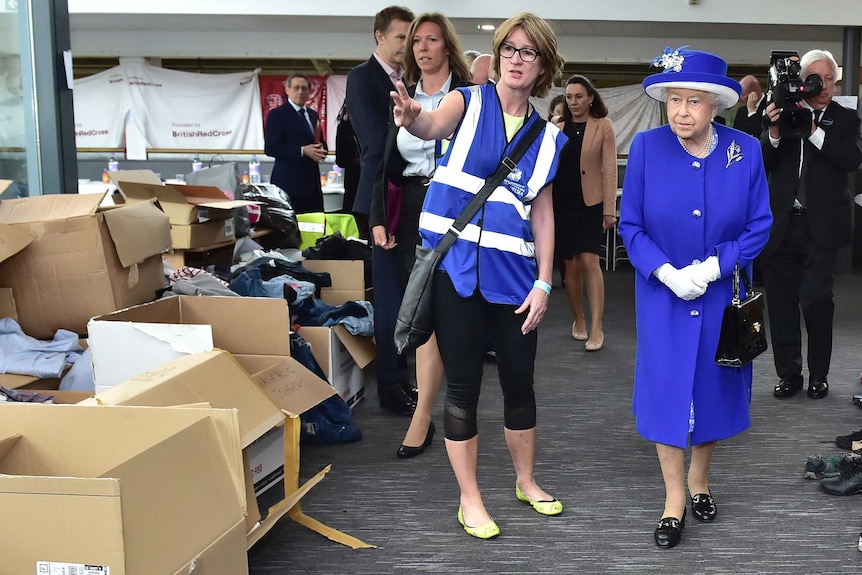Britain's Queen Elizabeth II (right) looks at donations collected for members of the community affected by the Grenfell Tower.