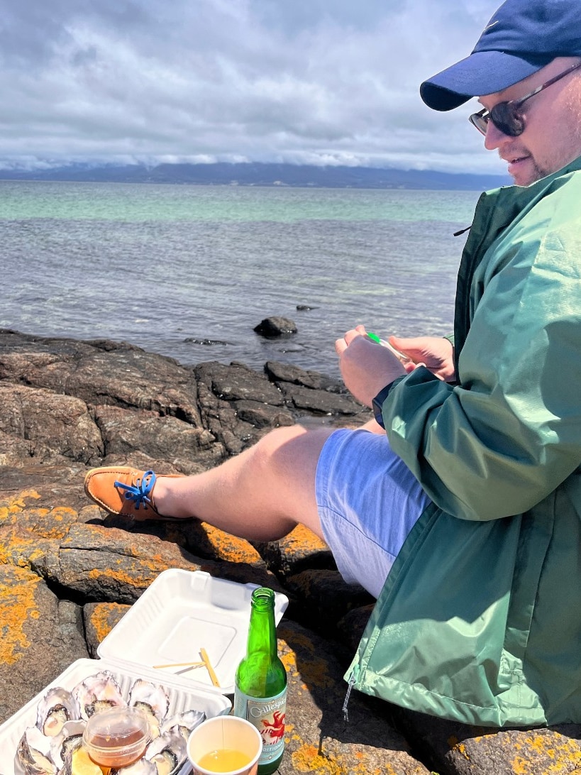 A man in a blue hat eats oysters