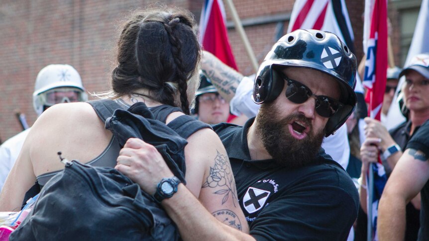 Right-wing supporter tries to move a female protester at a rally in Charlottesville, USA.