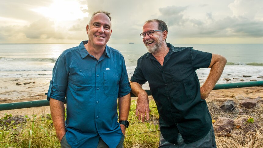 Andy Wharton and Tim Moore leaning on a railing overlooking the beach.
