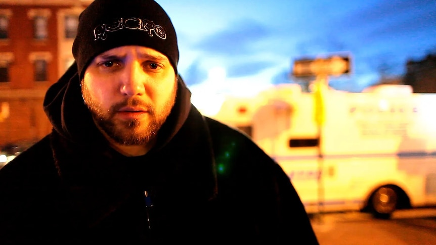 A man wearing a heavy jacket and beanie looks at the camera.