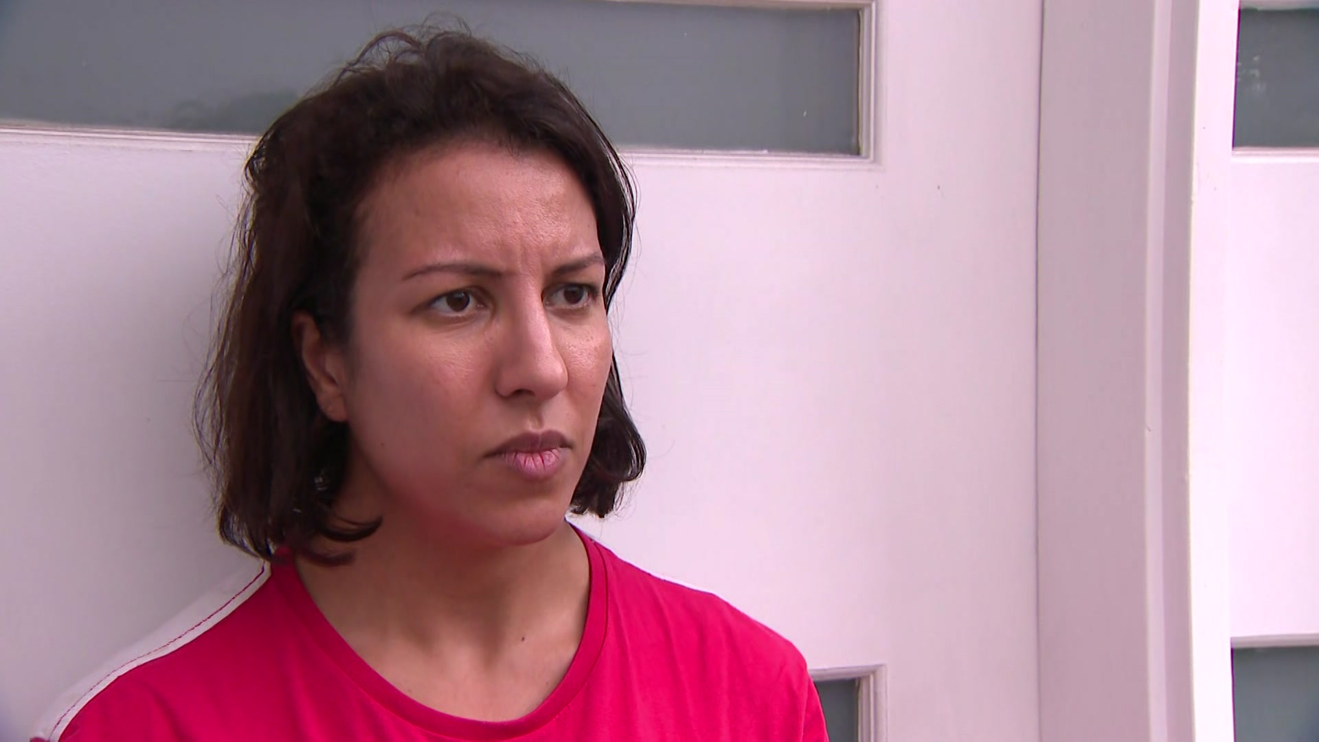 A woman in a red tshirt in front of a white door