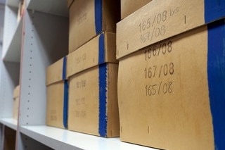 A wall lined with brown boxes with dates written on the front in black pen
