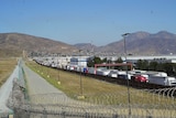 The US-Mexico border marked by a high, razor-wire fence.