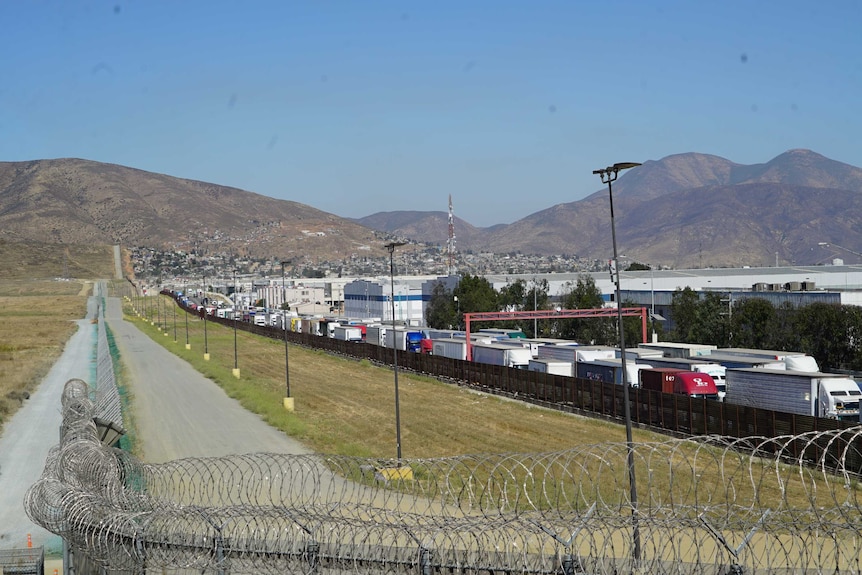 The US-Mexico border marked by a high, razor-wire fence.