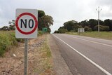 A speed sign on the side of a country road. Its numerals have been altered with tape so that it reads "No".