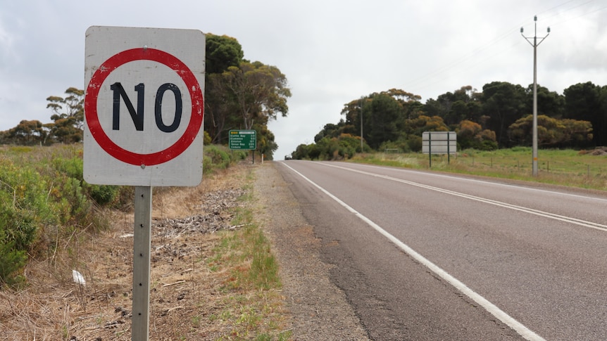 A speed sign on the side of a country road. Its numerals have been altered with tape so that it reads "No".