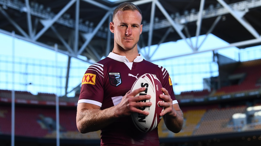 Queensland State of Origin captain Daly Cherry-Evans, holding a ball in two hands, posing for a promotional shoot