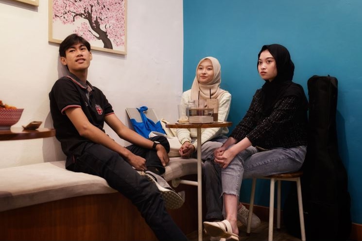 Three teenagers sit at a cafe together.
