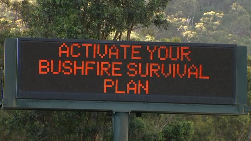 A roadside electronic sign with the words "Activate your bushfire survival plan" on it