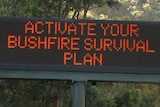 A roadside electronic sign with the words "Activate your bushfire survival plan" on it
